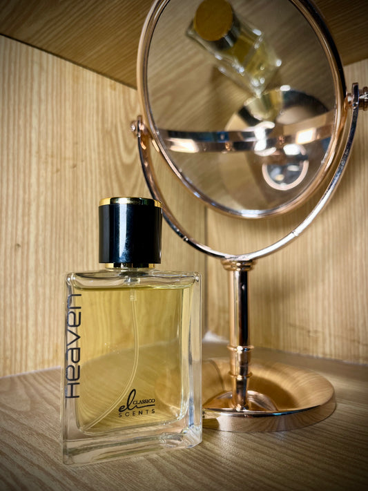 Perfume bottle labeled 'Heaven' next to a mirror on a wooden surface.