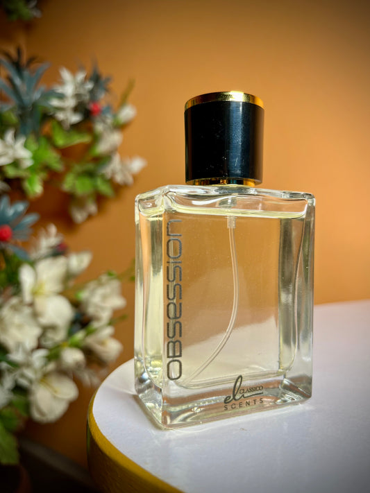 Perfume bottle labeled 'Obsession' on a table with a blurred floral background