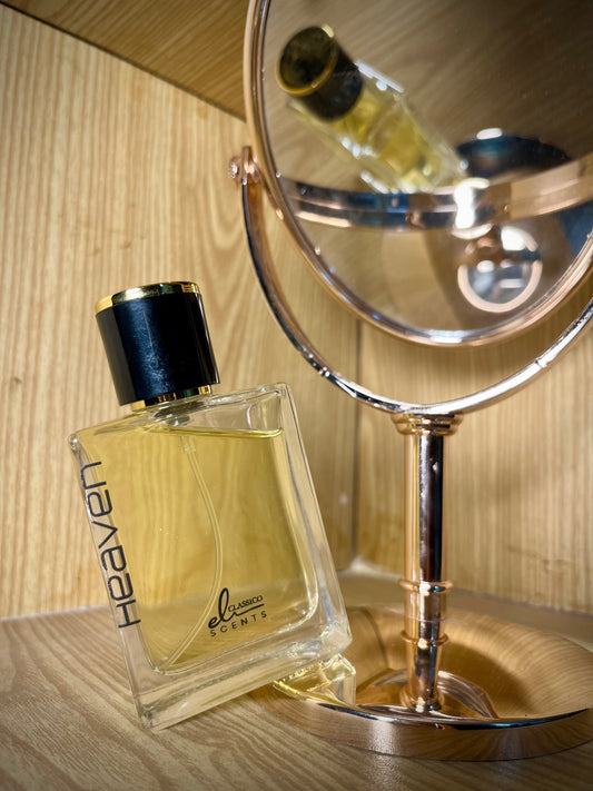 Perfume bottle labeled 'Heaven' next to a mirror on a wooden surface