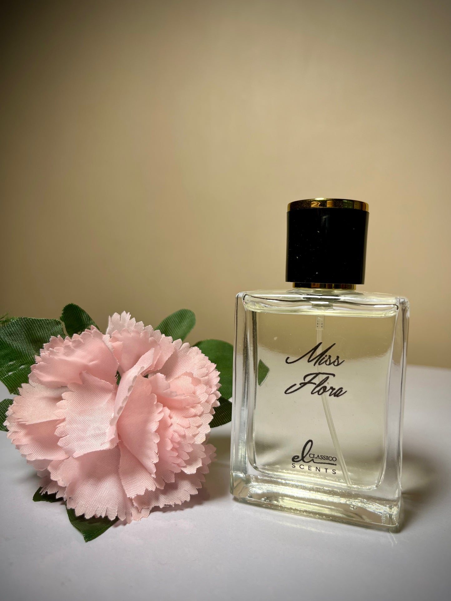 Perfume bottle labeled 'Miss Flora' with a pink flower on a neutral background