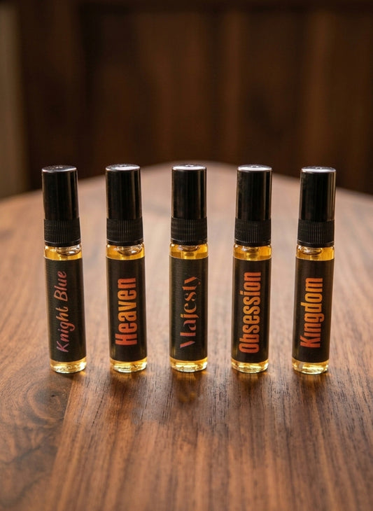 Five small bottles of perfume or cologne with black caps and labeled names on a wooden surface.